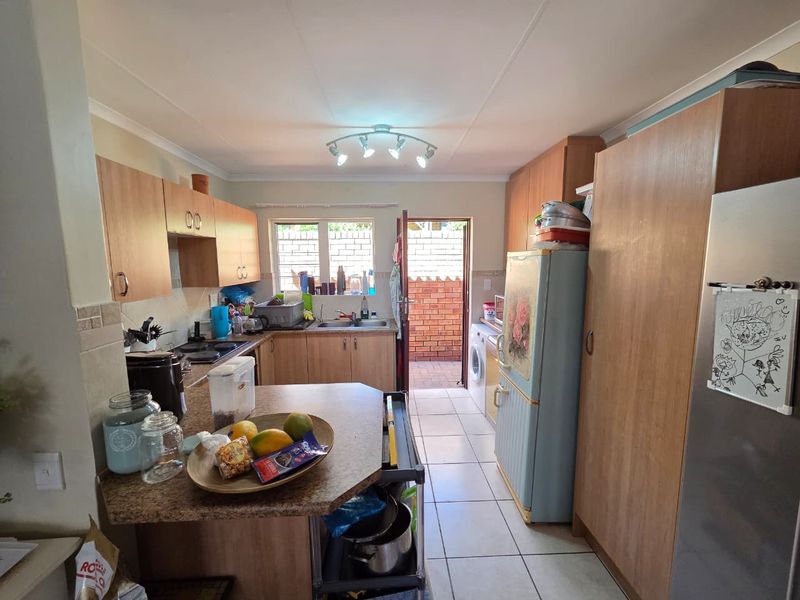 Functional kitchen featuring built-in cabinetry, laminate countertops, and tiled flooring, with direct access to an outdoor paved area.