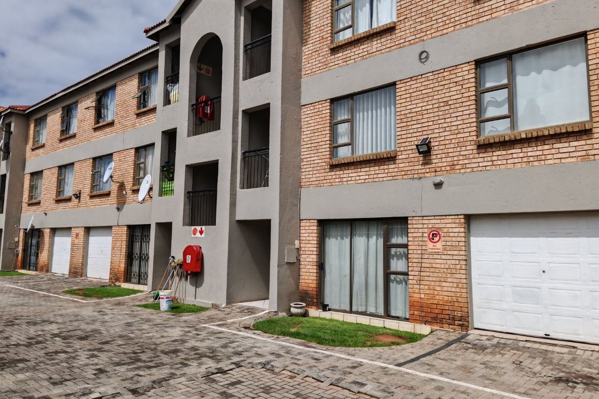 Exterior view of a multi-story commercial or residential complex featuring face brick facade, paved driveway, and integrated garage access.
