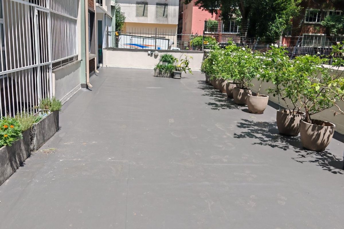 A spacious, open-air balcony featuring a clean, painted concrete surface and secure perimeter fencing, offering a functional outdoor area.