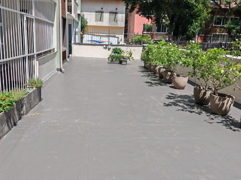 A spacious, open-air balcony featuring a clean, painted concrete surface and secure perimeter fencing, offering a functional outdoor area.