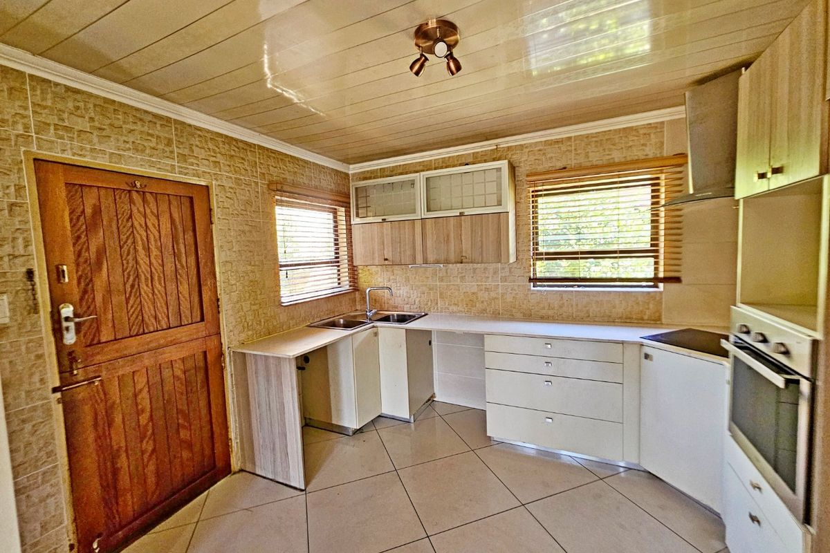 A functional kitchen featuring built-in cabinetry, integrated oven, extractor fan, and tiled flooring, offering a clean and practical layout for culinary activities.