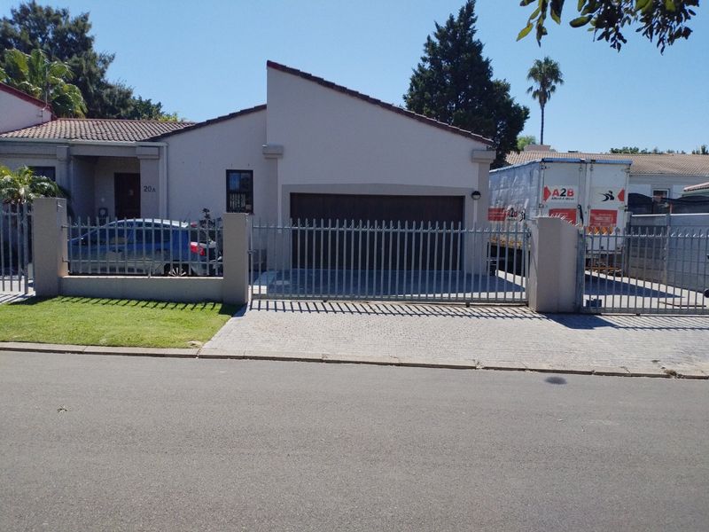 Front elevation of the property featuring a paved driveway, secure metal gate, and integrated garage.