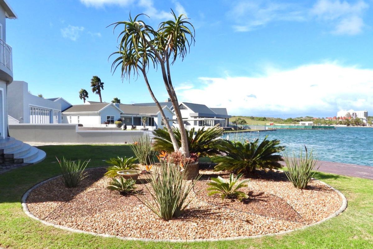 A well-maintained rear garden featuring landscaped beds, mature plants, and direct waterfront access, providing a serene outdoor living space.