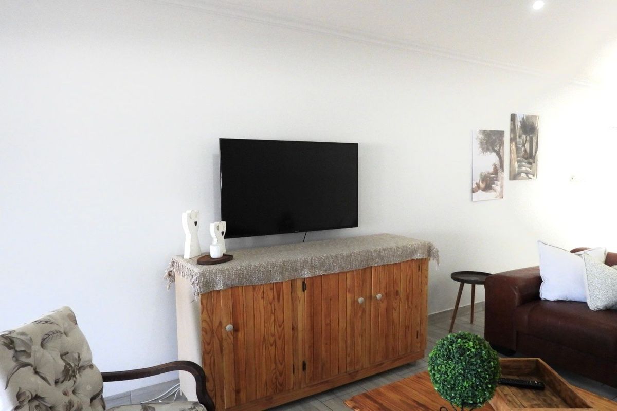 A bright living room featuring neutral tiled flooring and recessed downlighting, providing a clean and functional space for relaxation.