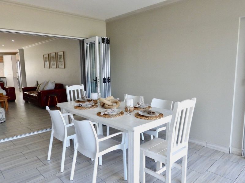 A covered patio area featuring tiled flooring and bi-fold doors that open into the main living space of the apartment.