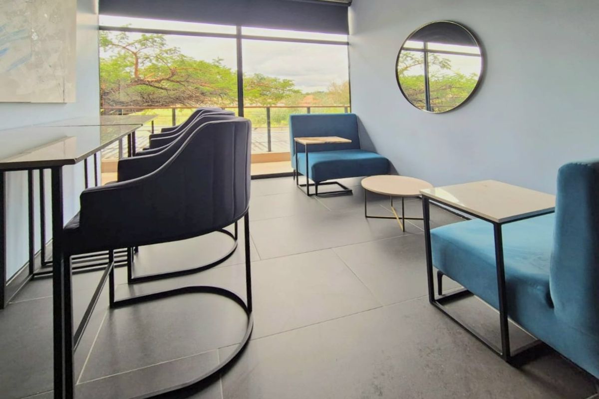 Modern commercial lounge area featuring large format floor tiles, floor-to-ceiling windows with natural light, and an exposed concrete architectural detail.