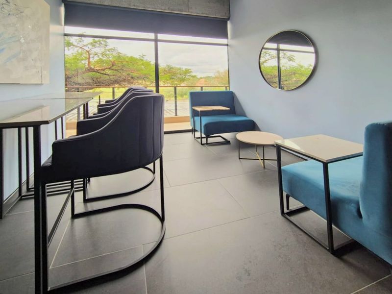 Modern commercial lounge area featuring large format floor tiles, floor-to-ceiling windows with natural light, and an exposed concrete architectural detail.