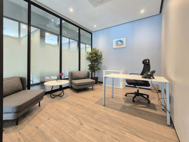 A modern professional office space featuring wood-look flooring, recessed lighting, and black-framed glass partitioning for a bright, contemporary workspace.
