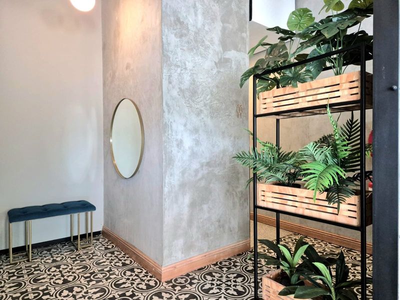 A modern commercial hallway featuring decorative patterned floor tiles, textured cement-finish walls, and timber skirting boards.