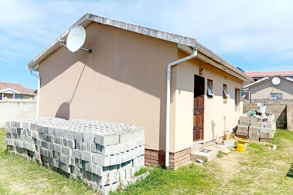 Rear view of the property showing the exterior wall, guttering system, and access door with surrounding yard space.