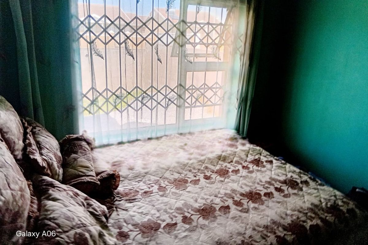 A bedroom featuring a window with a fitted security gate, providing natural light and security.