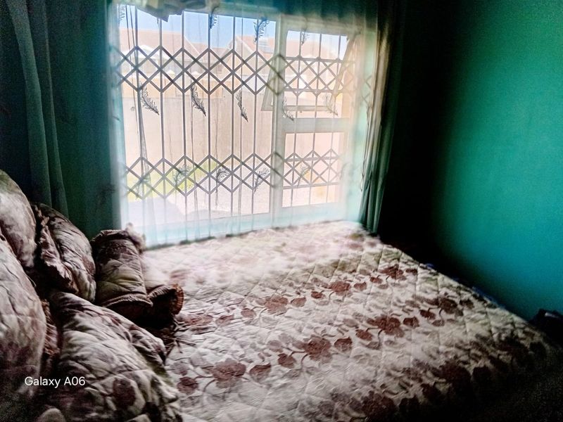 A bedroom featuring a window with a fitted security gate, providing natural light and security.
