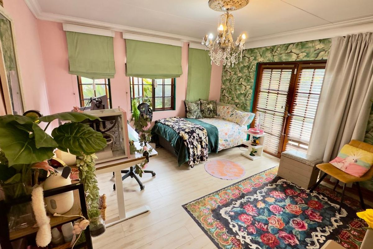 A bedroom featuring light wood-look flooring, decorative ceiling rose with chandelier, and double doors leading to the exterior.