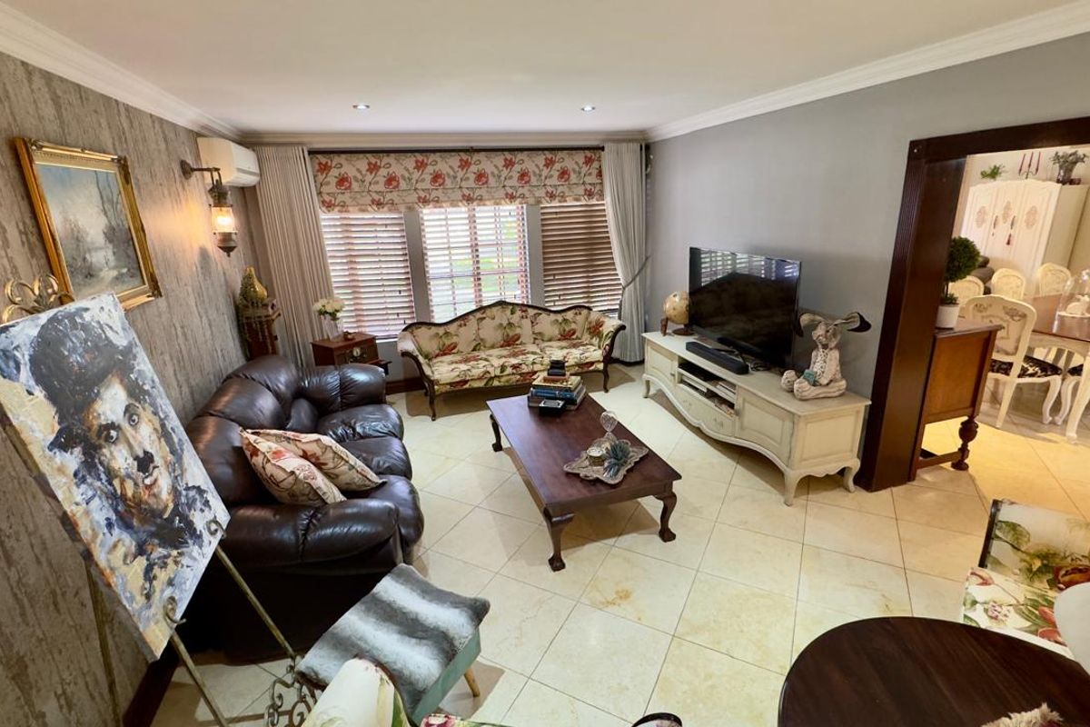 A spacious living room featuring tiled flooring, crown molding, and recessed lighting, with an open-plan flow leading into the adjacent dining area.