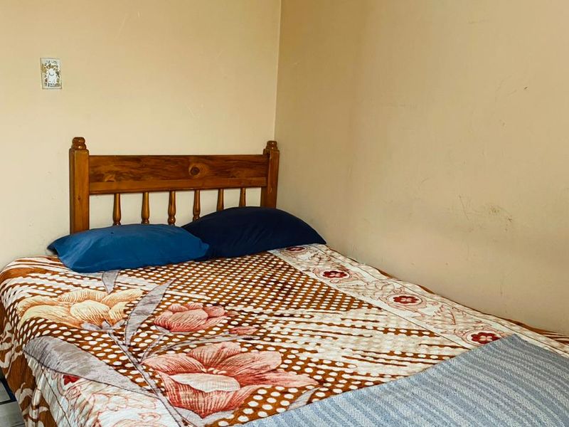 A compact bedroom featuring plain walls and a simple layout, suitable for a single bed setup.