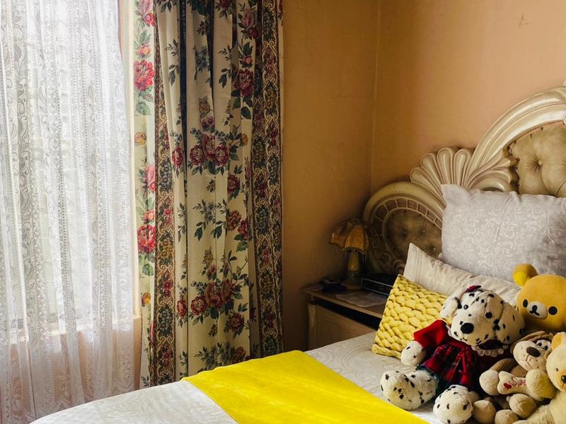 A bedroom featuring a timber ceiling and window, currently showing signs of wear including peeling paint on the walls.