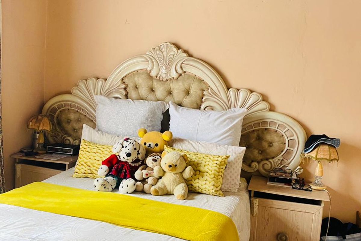 A bedroom featuring a timber ceiling, laminate flooring, and a decorative headboard. The walls show signs of minor plaster cracking.