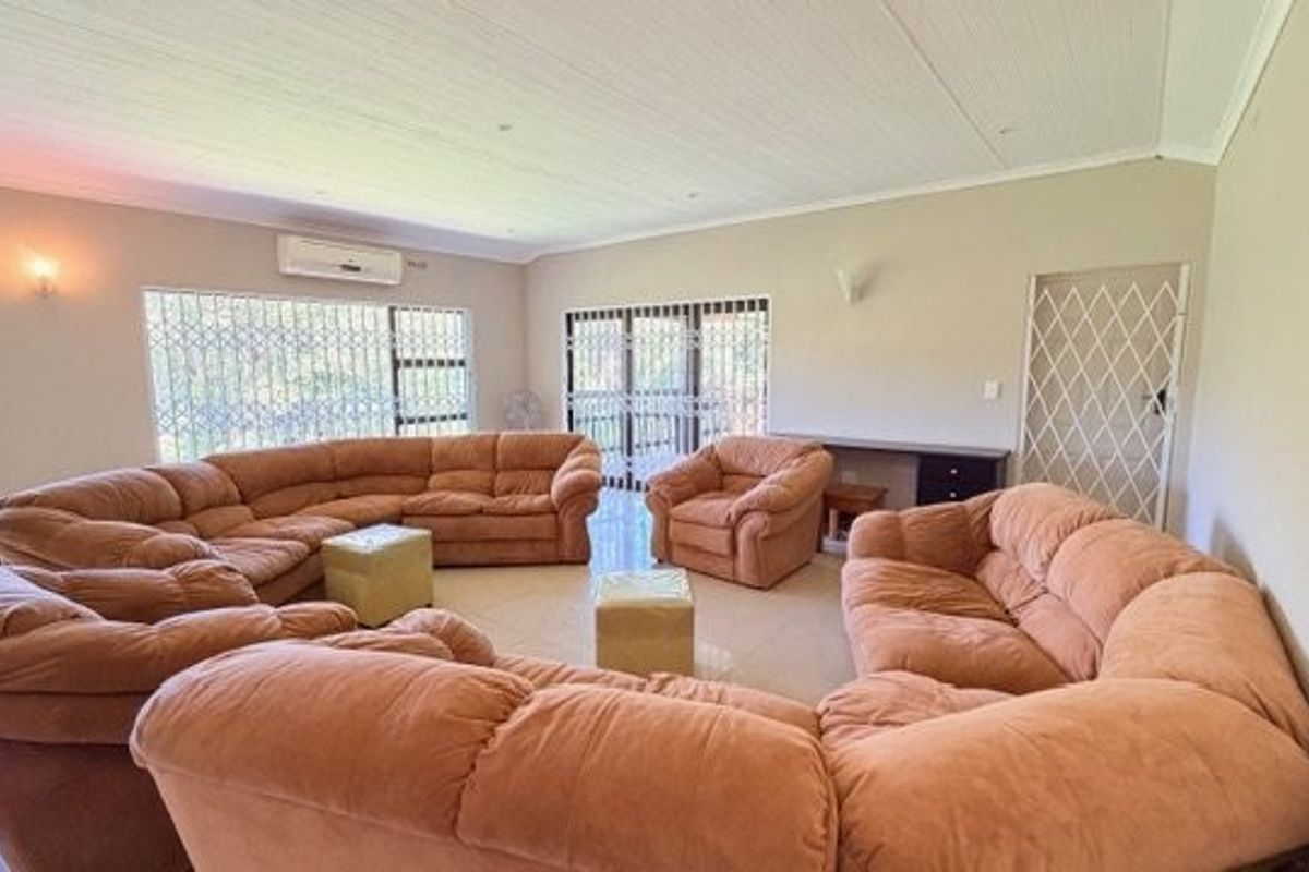 Spacious living room featuring tiled flooring, an integrated air conditioning unit, and a built-in desk area with secure access points.