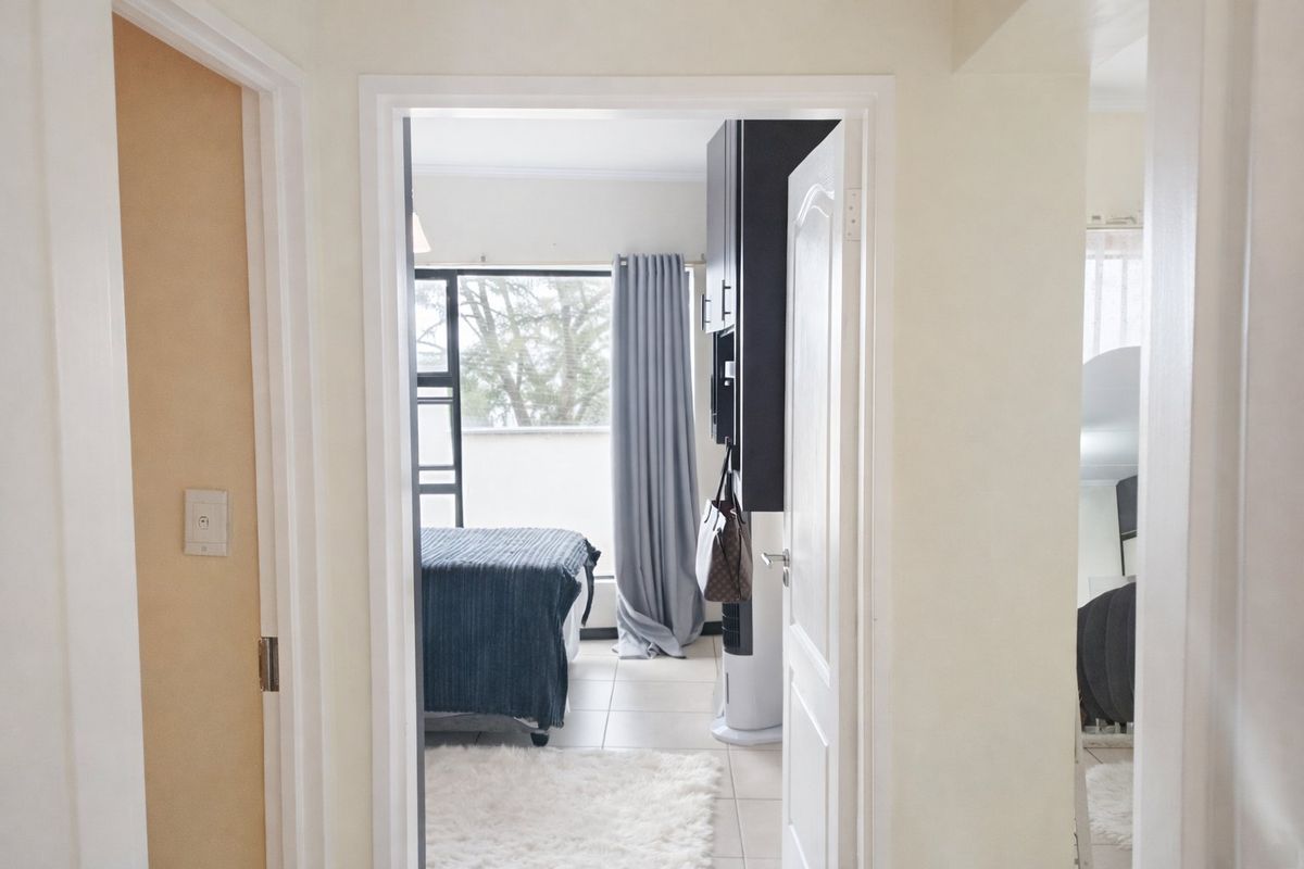 A view through a doorway into a bedroom featuring tiled flooring, built-in cabinetry, and a large window providing natural light.