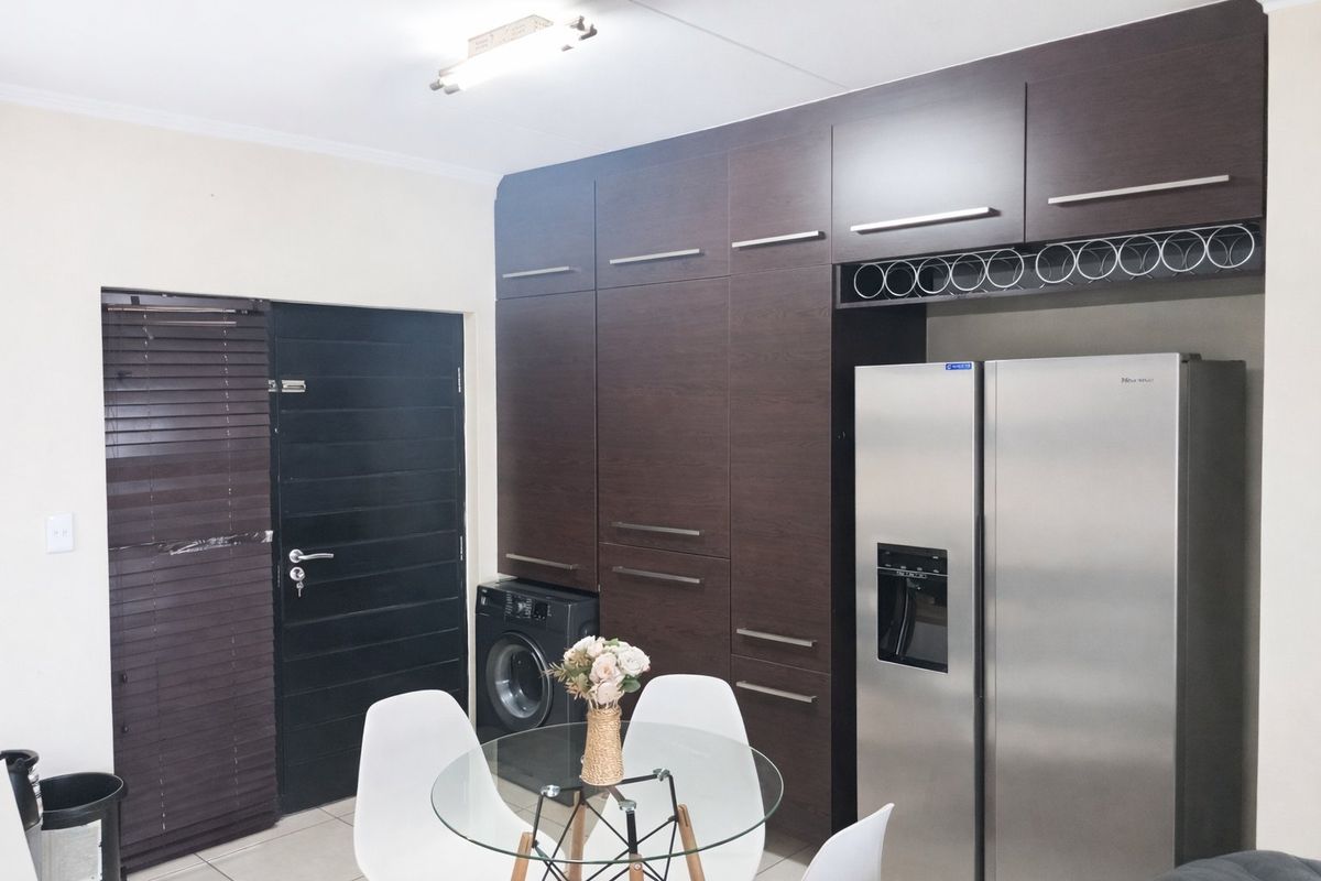A functional kitchen area featuring dark wood built-in cabinetry, integrated laundry space, and tiled flooring, providing a clean and organized utility layout.