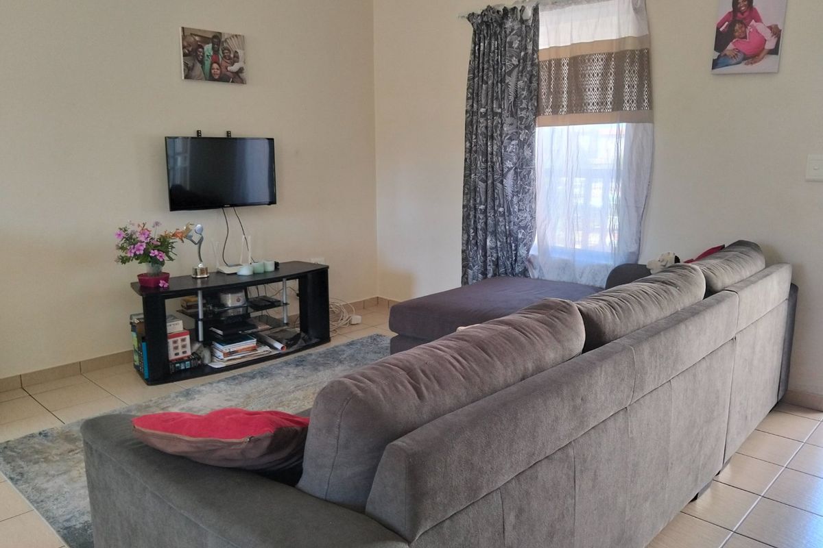 A functional living room featuring neutral walls and tiled flooring, providing a comfortable and versatile space for relaxation.