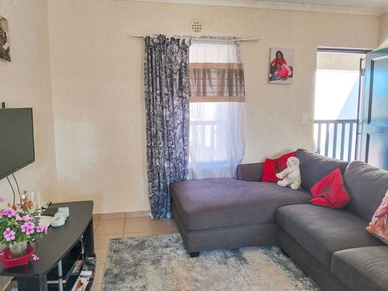 A living room area featuring tiled flooring and access to an outdoor balcony through a sliding door.