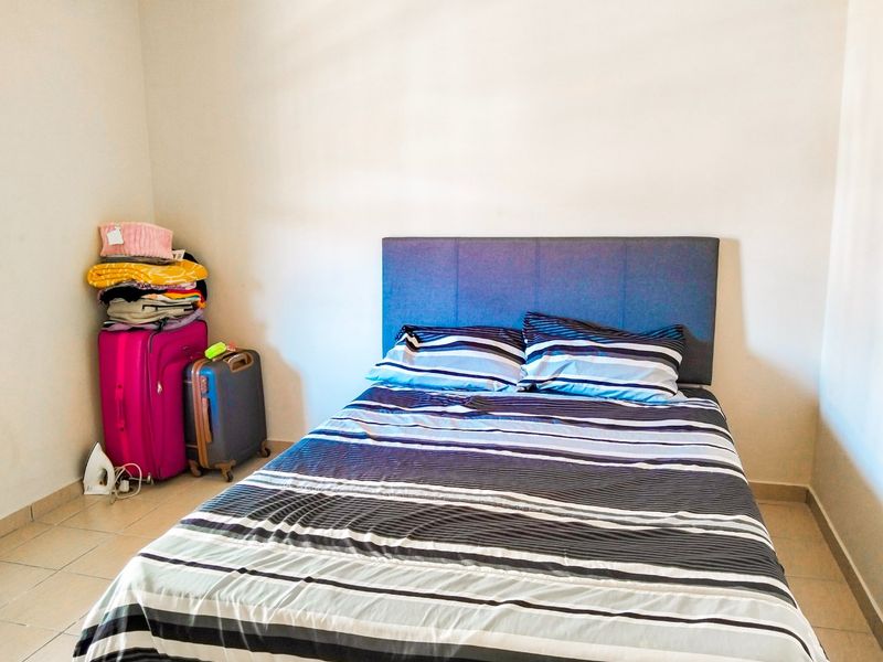 A simple bedroom featuring tiled flooring and neutral wall finishes, providing a functional space for rest.