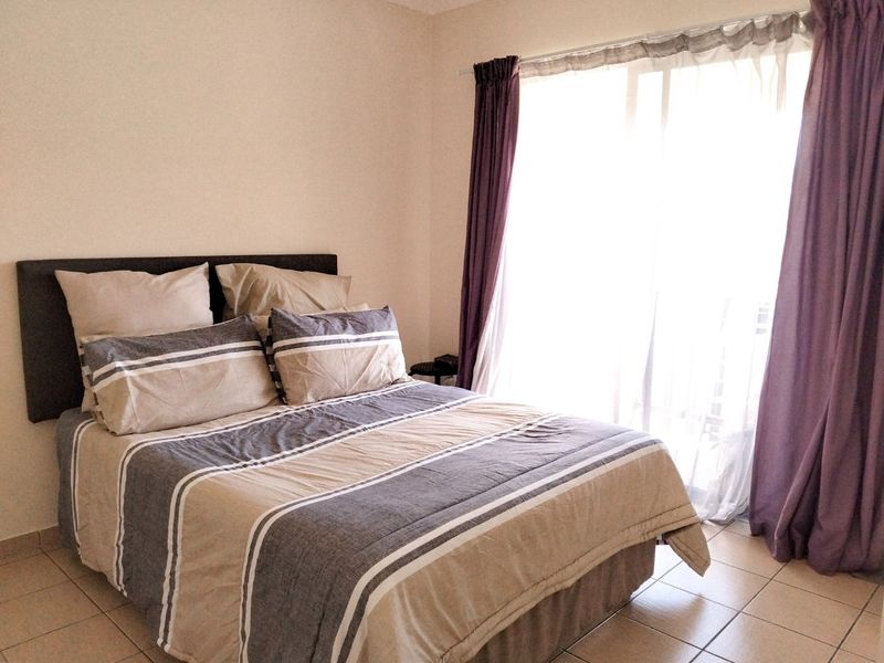 A bedroom featuring tiled flooring and a sliding glass door providing access to natural light.