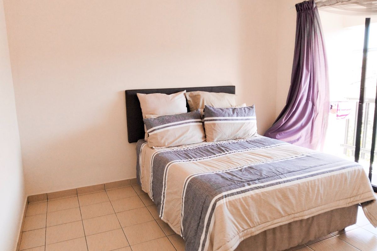 A functional bedroom featuring tiled flooring and a sliding glass door providing natural light and access to an outdoor area.