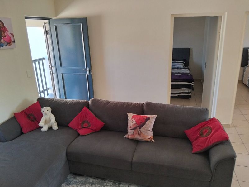 A living room area featuring tiled flooring with direct access to an external balcony and adjacent bedroom spaces.