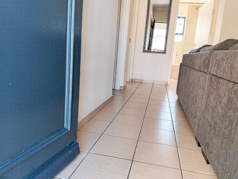 A tiled hallway providing access to adjacent rooms, featuring neutral wall finishes and standard architectural trim.