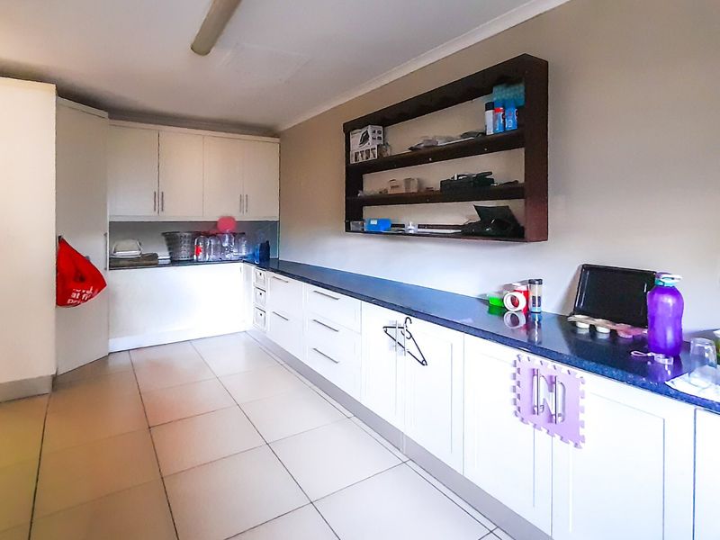 A functional laundry room featuring extensive built-in cabinetry, ample counter space, and tiled flooring, providing practical storage and utility workspace.