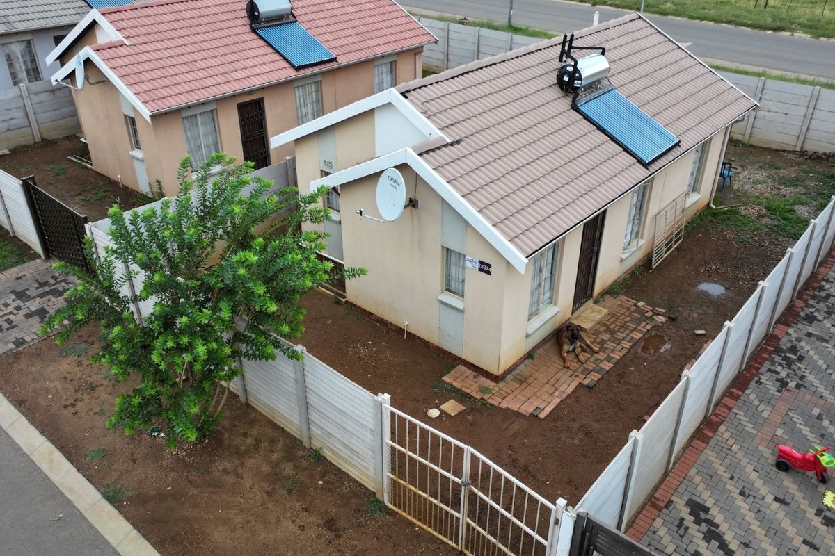Aerial view of a residential property featuring a tiled roof with a solar water heater, enclosed by precast concrete boundary walls.