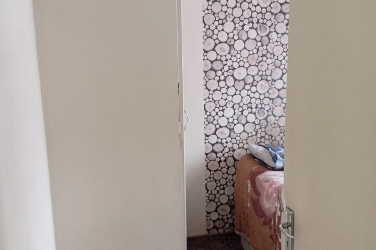 A view through a doorway into a bedroom featuring a decorative log-patterned accent wall.