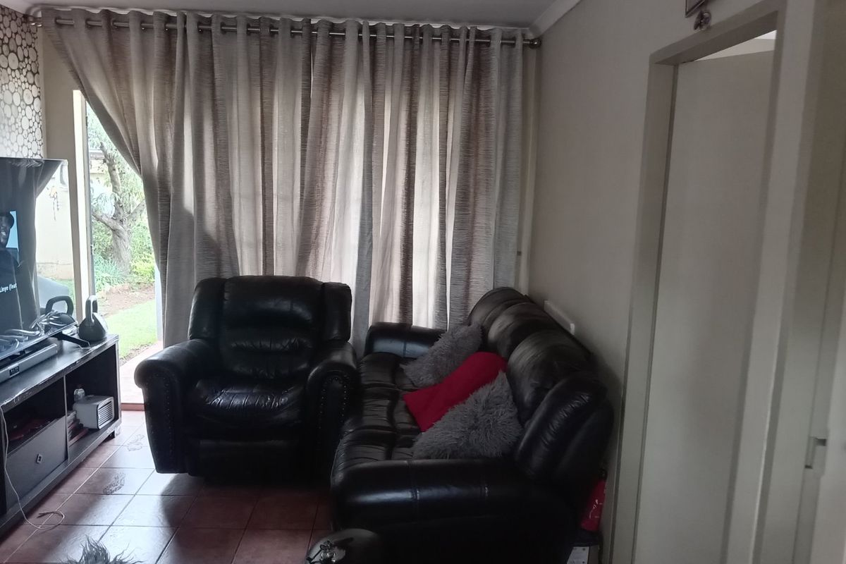 A living room featuring tiled flooring and large sliding glass doors with curtains, providing direct access to the outdoor area.
