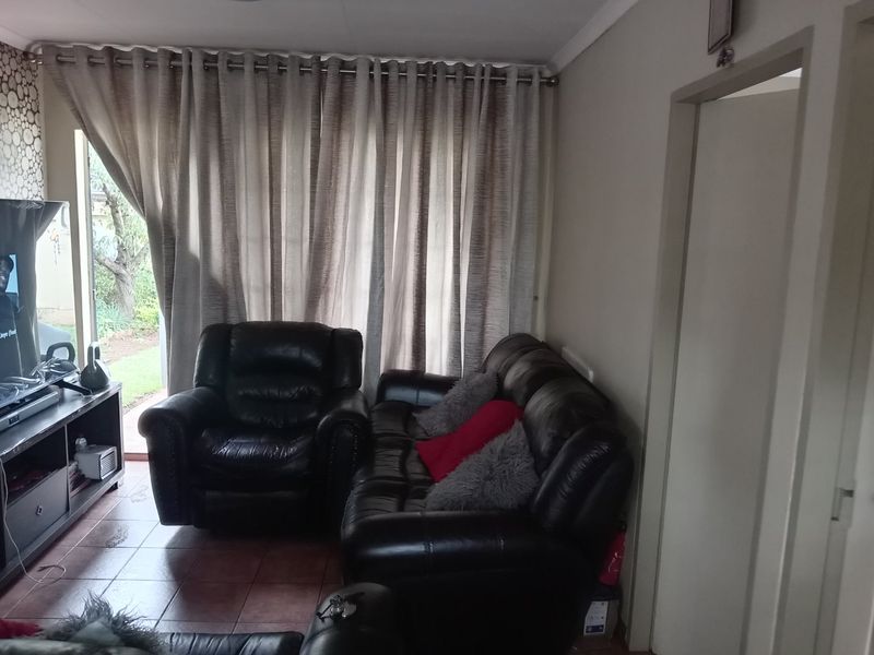 A living room featuring tiled flooring and large sliding glass doors with curtains, providing direct access to the outdoor area.
