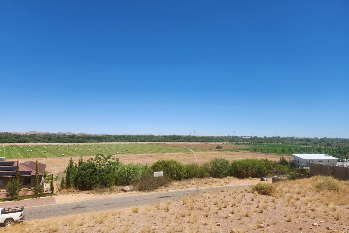 A wide-angle view overlooking a rural landscape with open fields, vegetation, and a local access road.