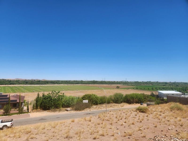 A wide-angle view overlooking a rural landscape with open fields, vegetation, and a local access road.