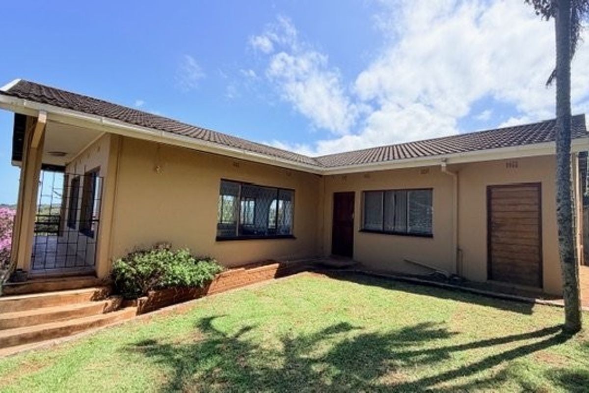 Rear view of the house featuring a tiled roof, concrete steps, and a small garden area with brick planter.