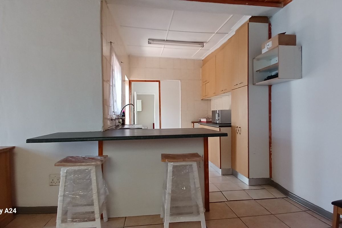 A functional kitchen featuring light wood cabinetry, a breakfast bar counter, and tiled flooring, providing a practical layout for daily meal preparation.