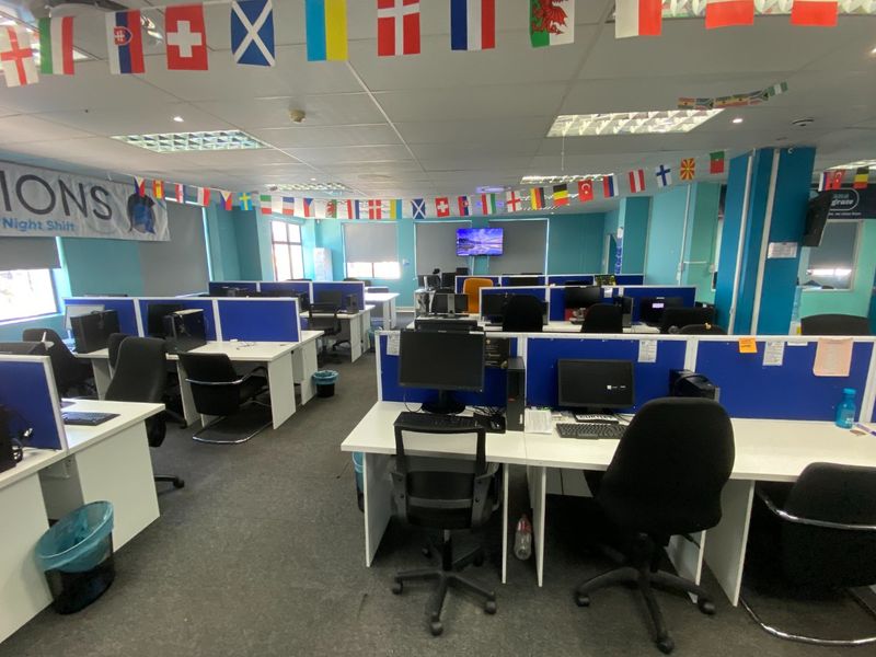 Open-plan commercial office space featuring multiple workstations with built-in partitions, suspended ceilings, and carpeted flooring.