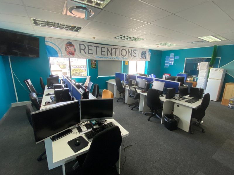 Open-plan commercial office space featuring multiple workstations with built-in partitions, suspended ceilings, and recessed lighting.