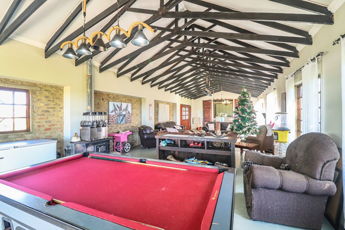 Spacious living area featuring a high vaulted ceiling with exposed timber trusses, an exposed brick feature wall, and a built-in wood burning stove.