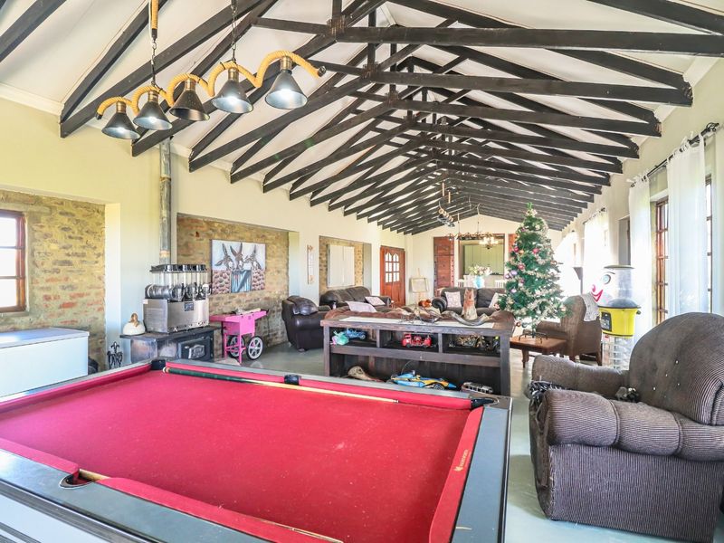 Spacious living area featuring a high vaulted ceiling with exposed timber trusses, an exposed brick feature wall, and a built-in wood burning stove.