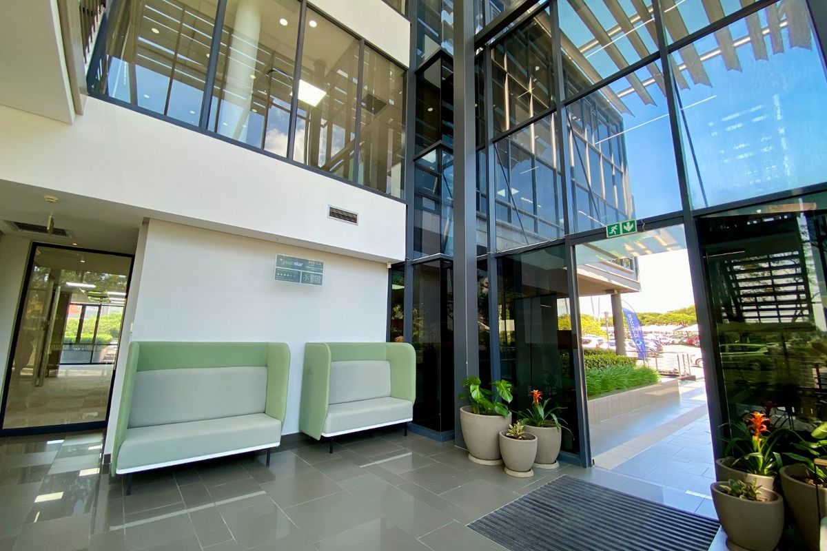 Modern commercial building entrance lobby featuring high ceilings, extensive glass curtain walling, and polished tiled flooring, providing a bright and professional reception area.