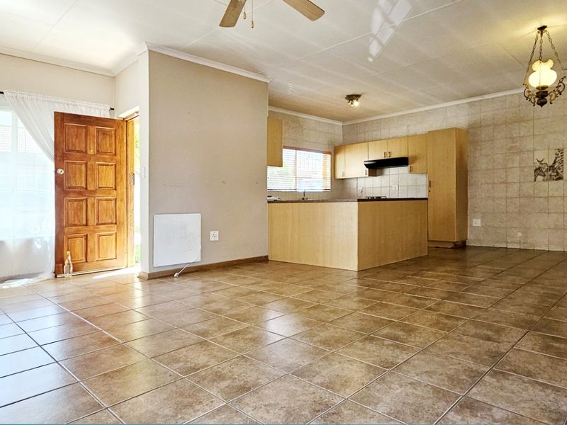 Spacious open-plan living and kitchen area featuring tiled flooring, built-in cabinetry, and direct access to the exterior.