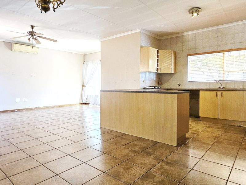 Spacious open-plan living and kitchen area featuring tiled flooring, built-in cabinetry, a central island, and a ceiling fan.