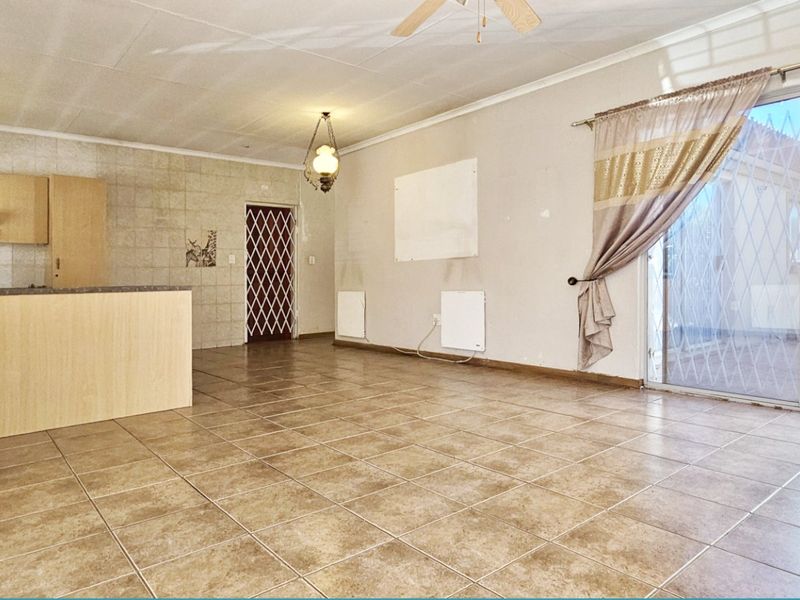 Open-plan living and kitchen area featuring tiled flooring, built-in cabinetry, and sliding glass doors leading to an outdoor patio space.