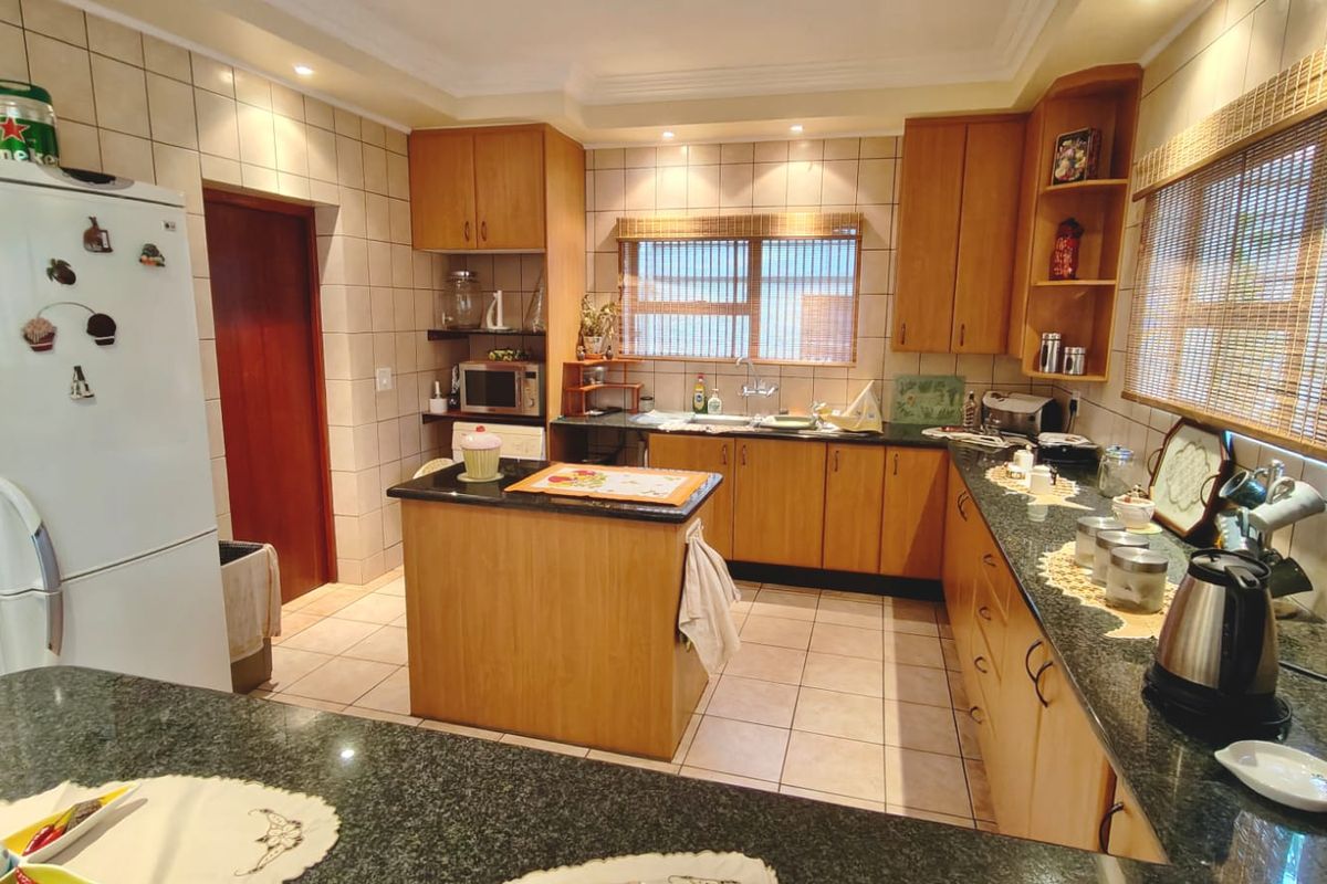 A functional kitchen featuring wooden cabinetry, granite countertops, a central island, and tiled finishes throughout.