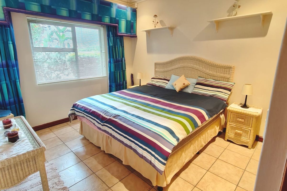 A bedroom featuring ceramic tile flooring, window blinds, and wall-mounted shelving, offering a functional space with potential for modern updates.